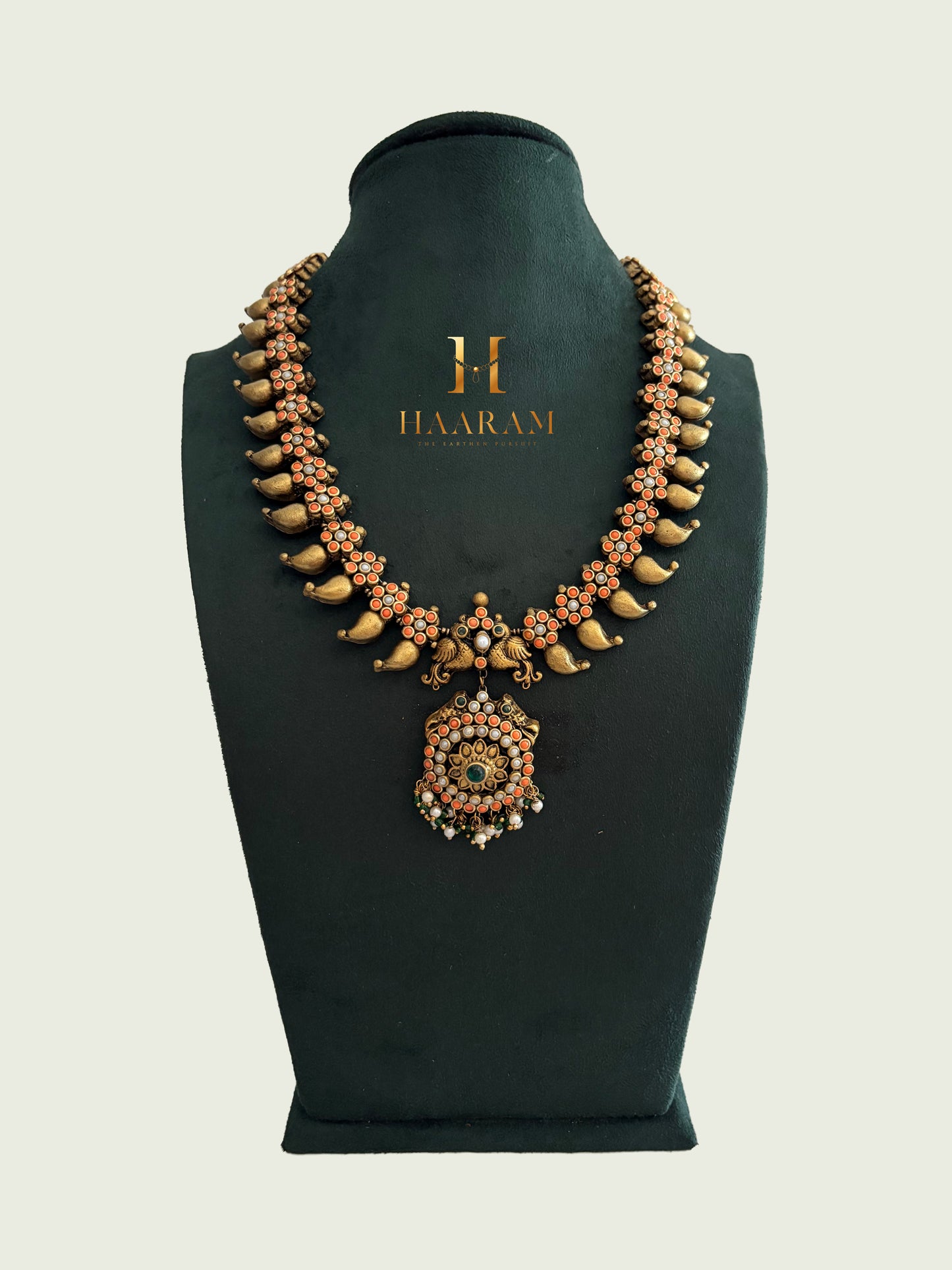 Terracotta necklace with gold tusk design, floral beads, and round pendant from Haarambyyashh.