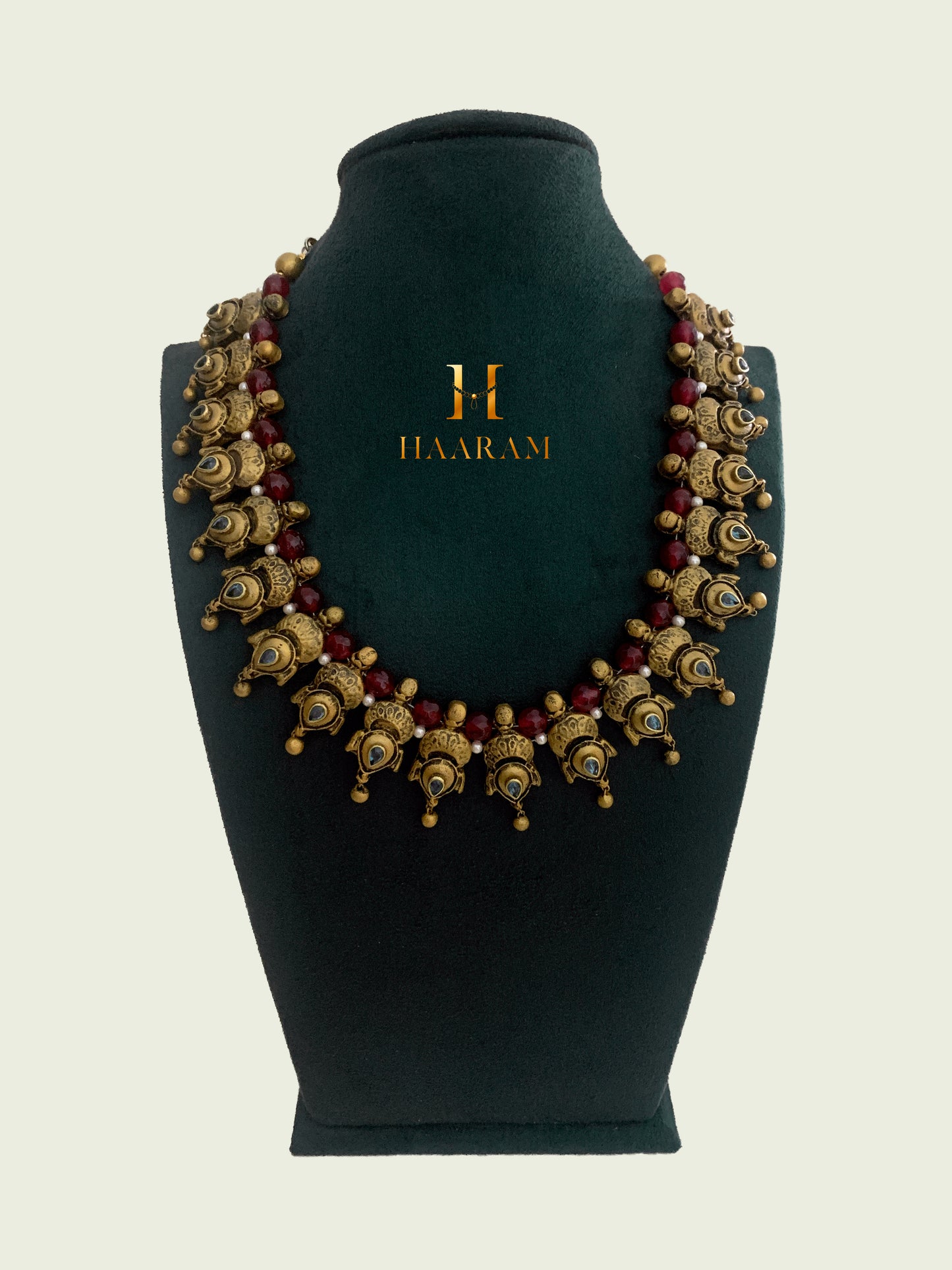 Traditional Terracotta necklace from Haaram by yashh. Features intricate peacock motifs and red bead accents, perfect for cultural and festive occasions. Elegant and detailed Indian jewelry design.