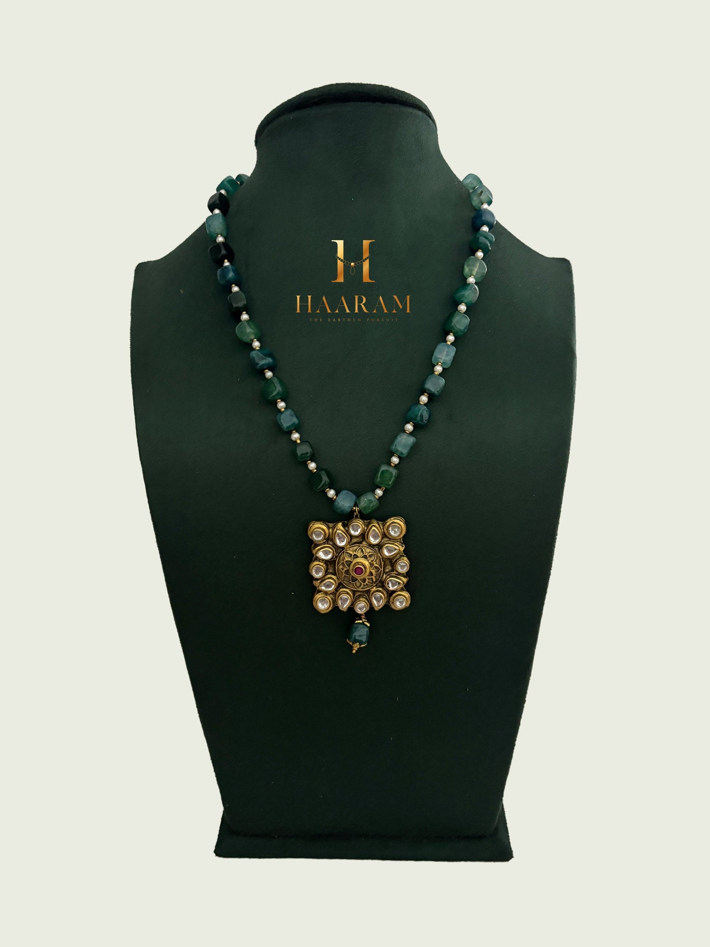 Green beaded necklace with a gold terracotta pendant by branded 'Haarambyyashh'.
