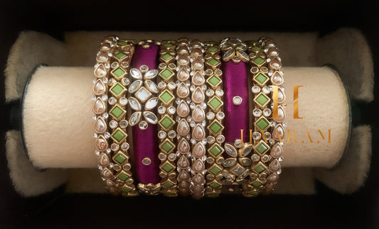 Purple and gold silk thread bangles with sparkling stones displayed on a wooden stand.