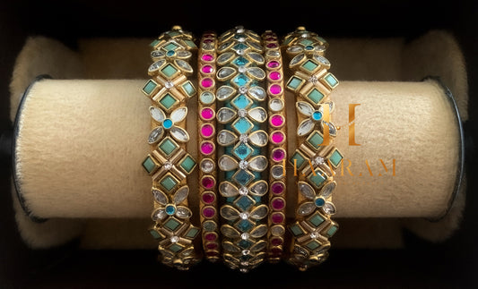 Multicolored silk thread bangles with stonework displayed on a wooden stand.