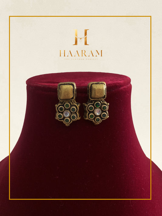 Antique-style geometric earrings by Haarambyyashh displayed on a red stand.