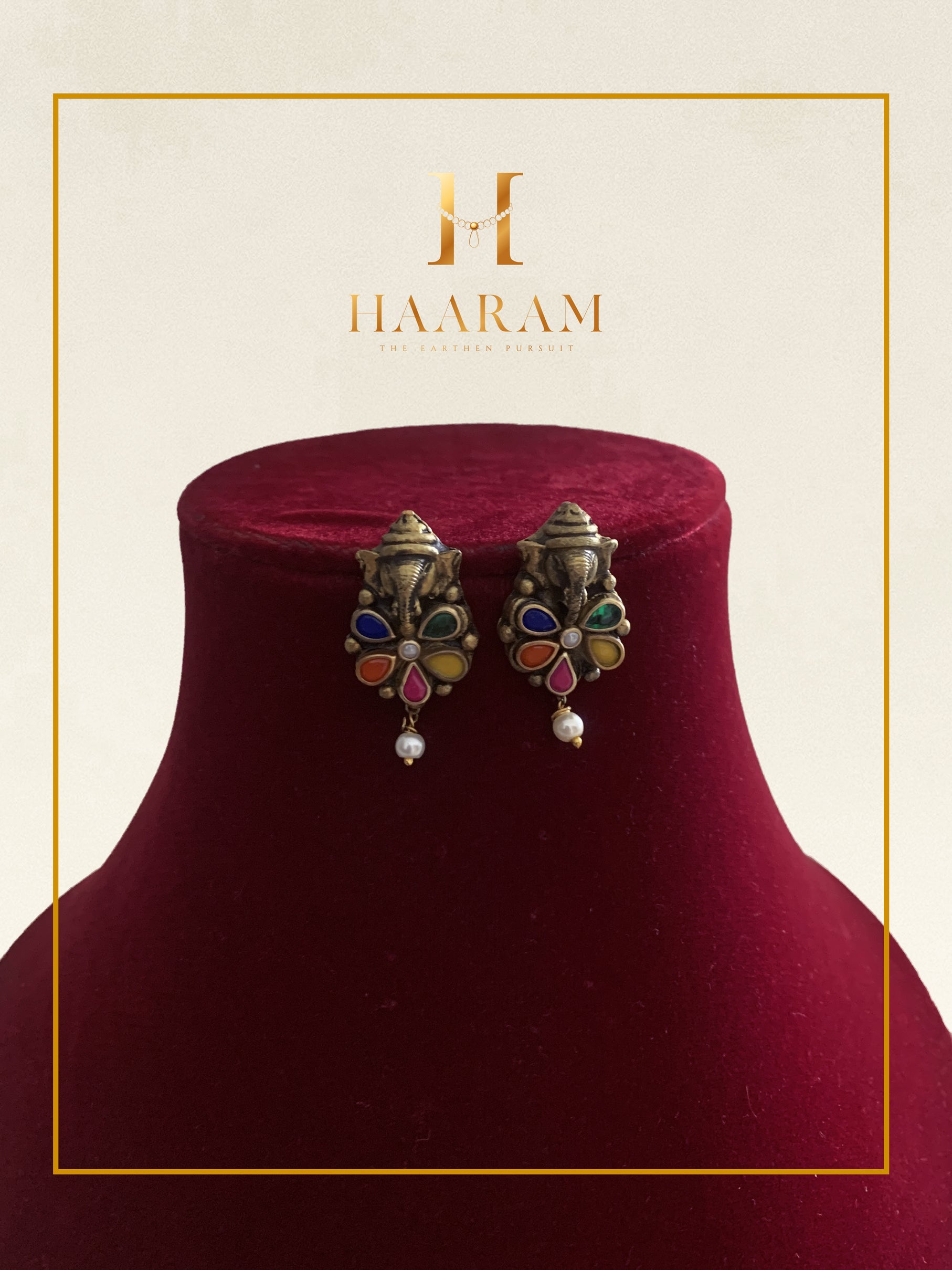 Multi-stone earrings with vibrant accents and pearl drops displayed on a red stand.