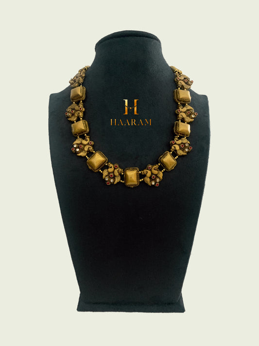 Antique gold-plated necklace from Haaram by yashh. Traditional Indian design featuring square and floral motifs,  adorned with intricate detailing and embellishments, perfect for cultural and festive occasions.