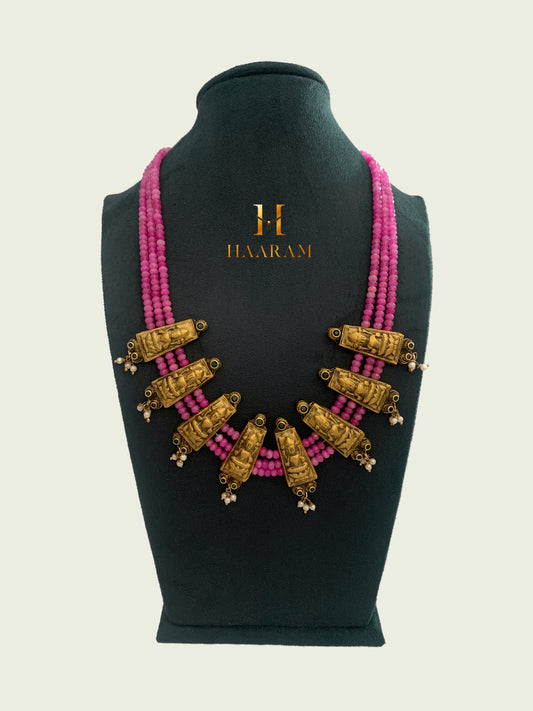 Lakshmi terracotta jewelry necklace with Three line pink beads and gold-plated deity pendants from Haarambyyashh. Traditional Indian design featuring intricate religious motifs, ideal for cultural and festive occasions.