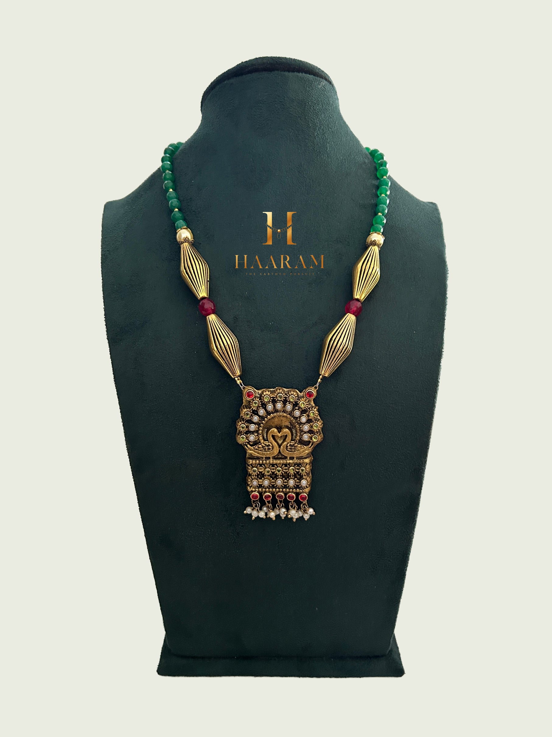 Traditional Terracotta necklace with antique gold pendant featuring a peacock motif, adorned with red and green gemstones from Haarambyyashh