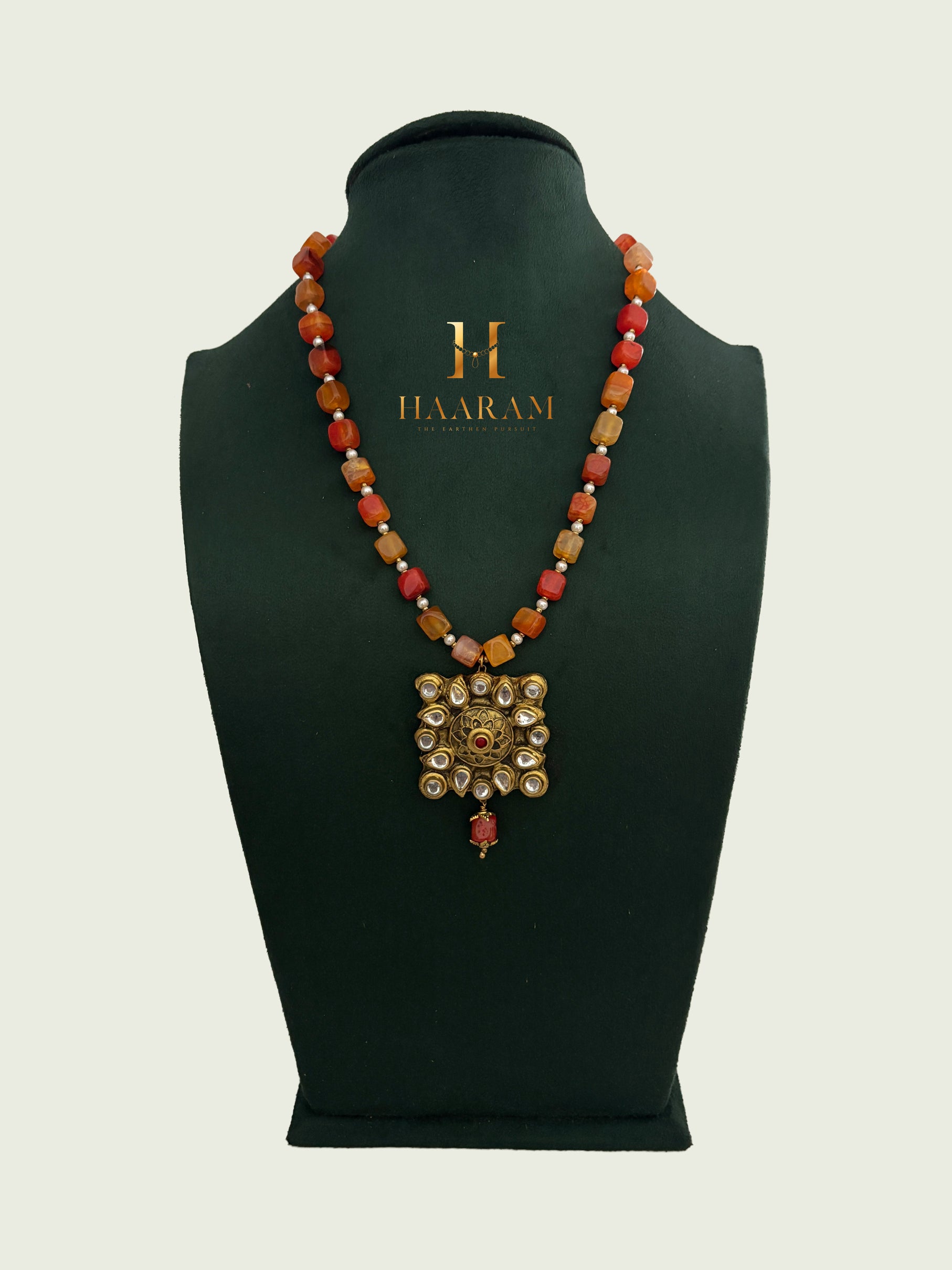 Orange beaded necklace with a gold terracotta pendant by branded 'Haarambyyashh'.