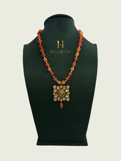 Orange beaded necklace with a gold terracotta pendant by branded 'Haarambyyashh'.