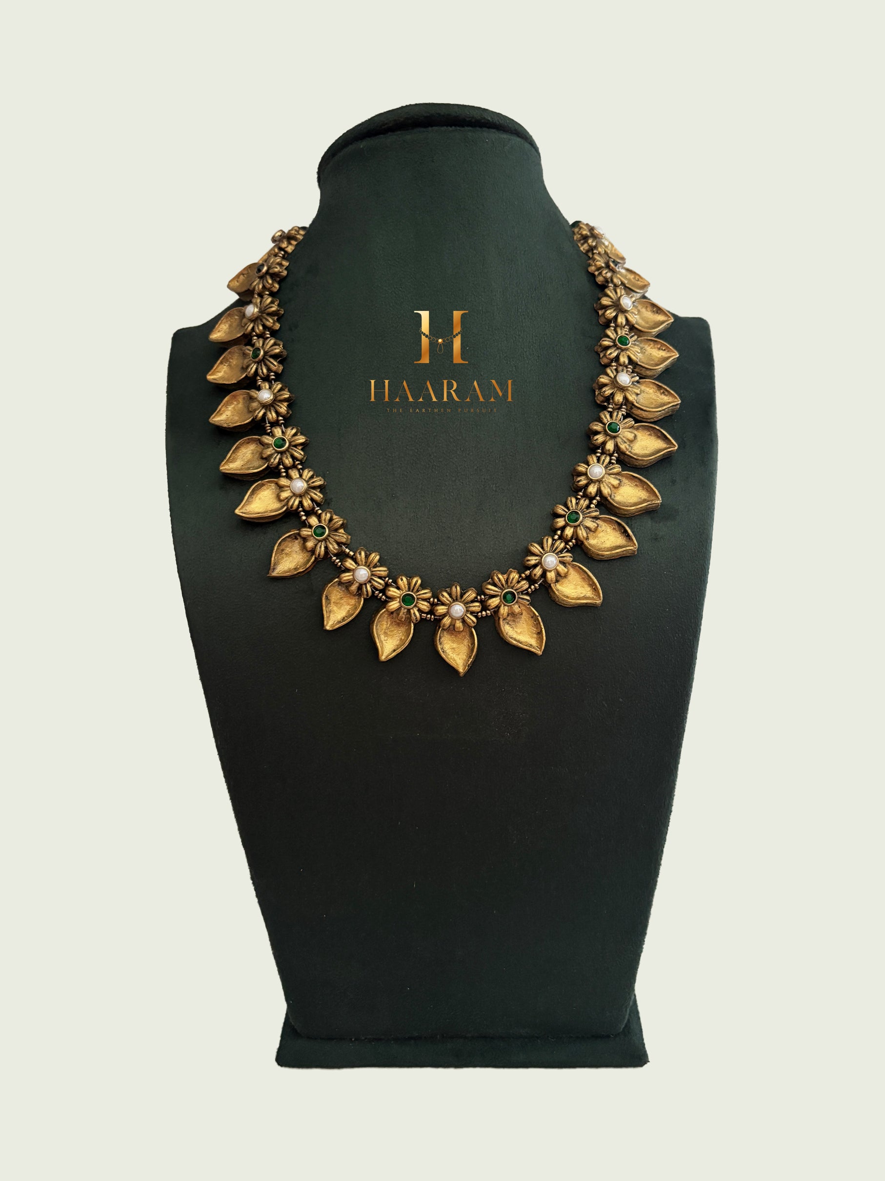 Terracotta necklace with mango gold pattern on green mannequin