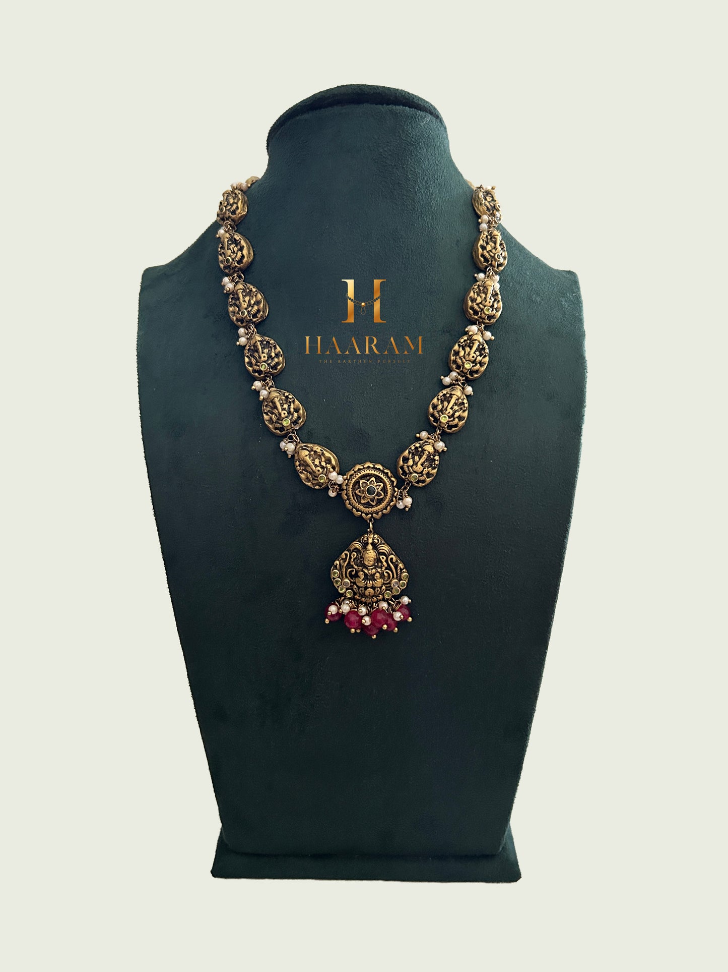 Antique Terracotta necklace with a Lakshmi motif pendant, featuring intricate floral designs, pearls, and ruby bead accents from Haarambyyashh